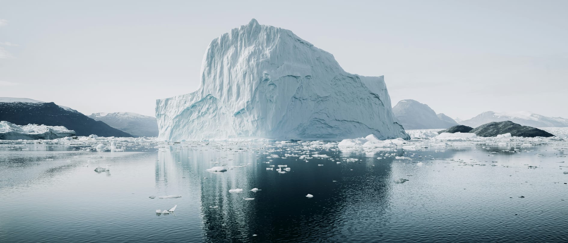 A Greenland iceberg on a calm, dark sea surrounded by drifting floes – meltwater from the Greenland ice sheet freshens the surface water of the North Atlantic