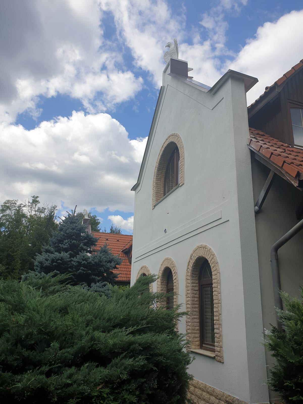 Gable elevation of a family house with a GWR NANO INSULATION® coating, the eagle sculpture at the apex and arched windows in rusticated stone surrounds, Dunabogdány