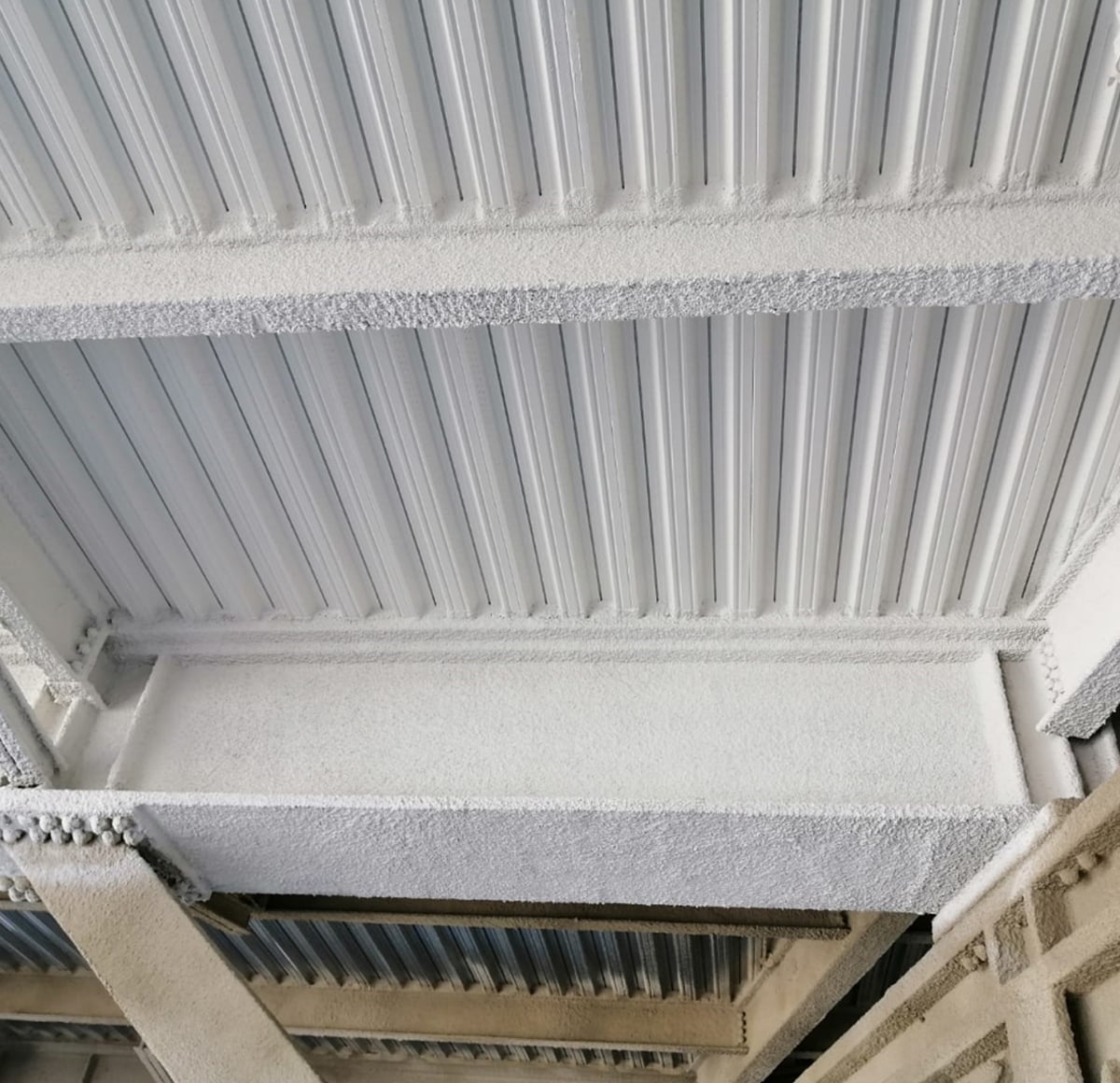 GWR NANO INSULATION® completed coating on trapezoidal steel decking and structural beams, Qatari stadium — uniform white texture, close view