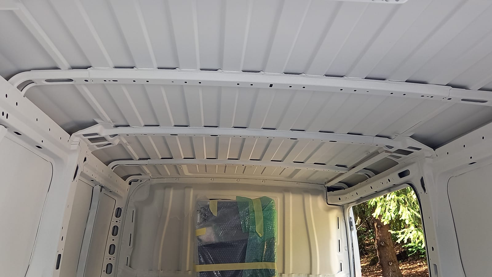 Light commercial vehicle cargo area with a GWR NANO INSULATION® interior coating — coated roof panel, perforated roof bows and side panels, rear doors open