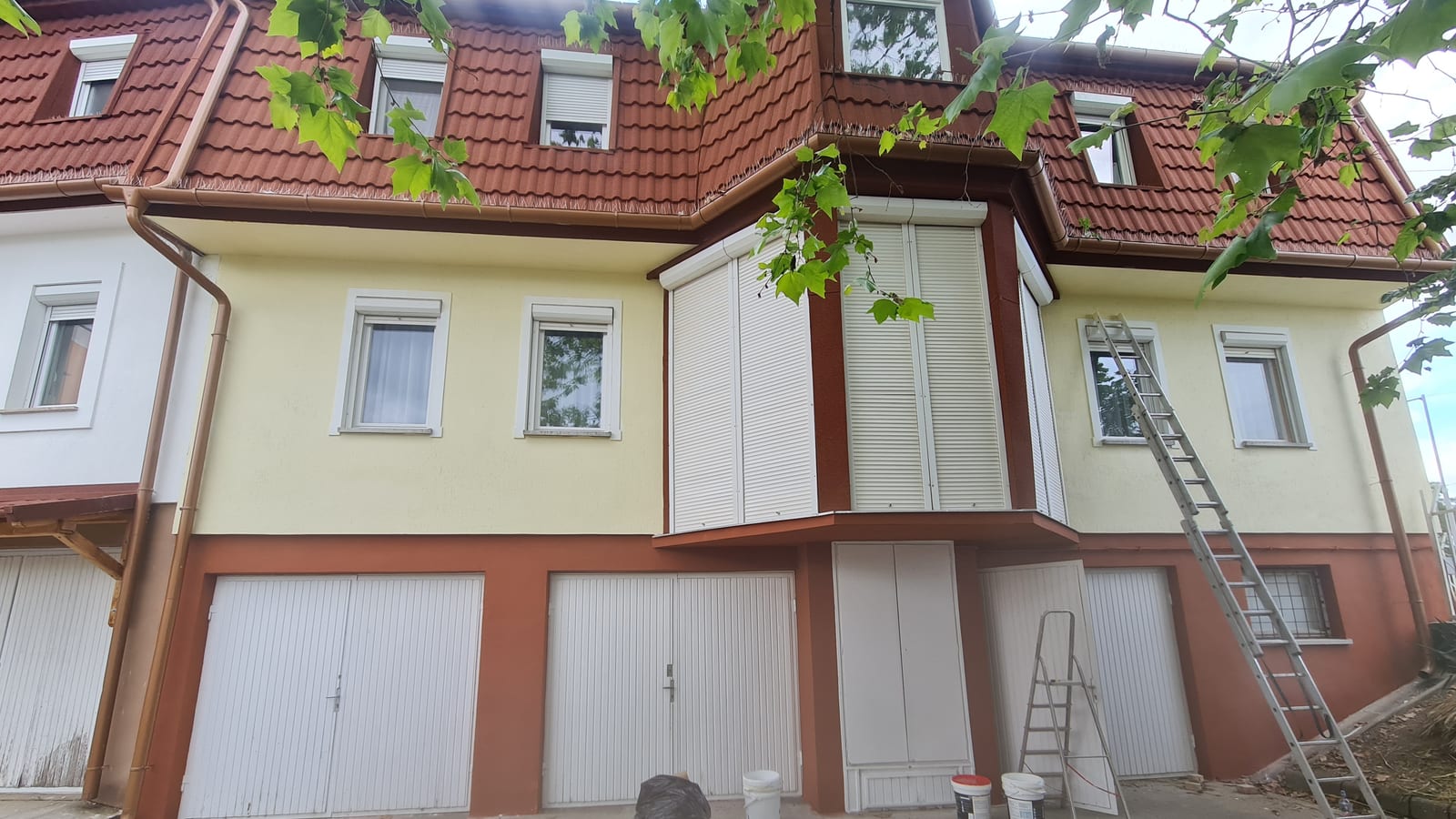 Two-colour GWR NANO INSULATION® coated facade of a family house with a converted roof space, oriel and garages, worked from a ladder, Paks