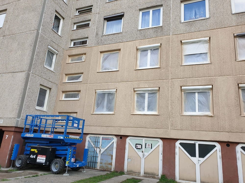 Multi-storey panel block facade partially coated with GWR NANO INSULATION®, self-propelled lift platform — treated and untreated surface side by side