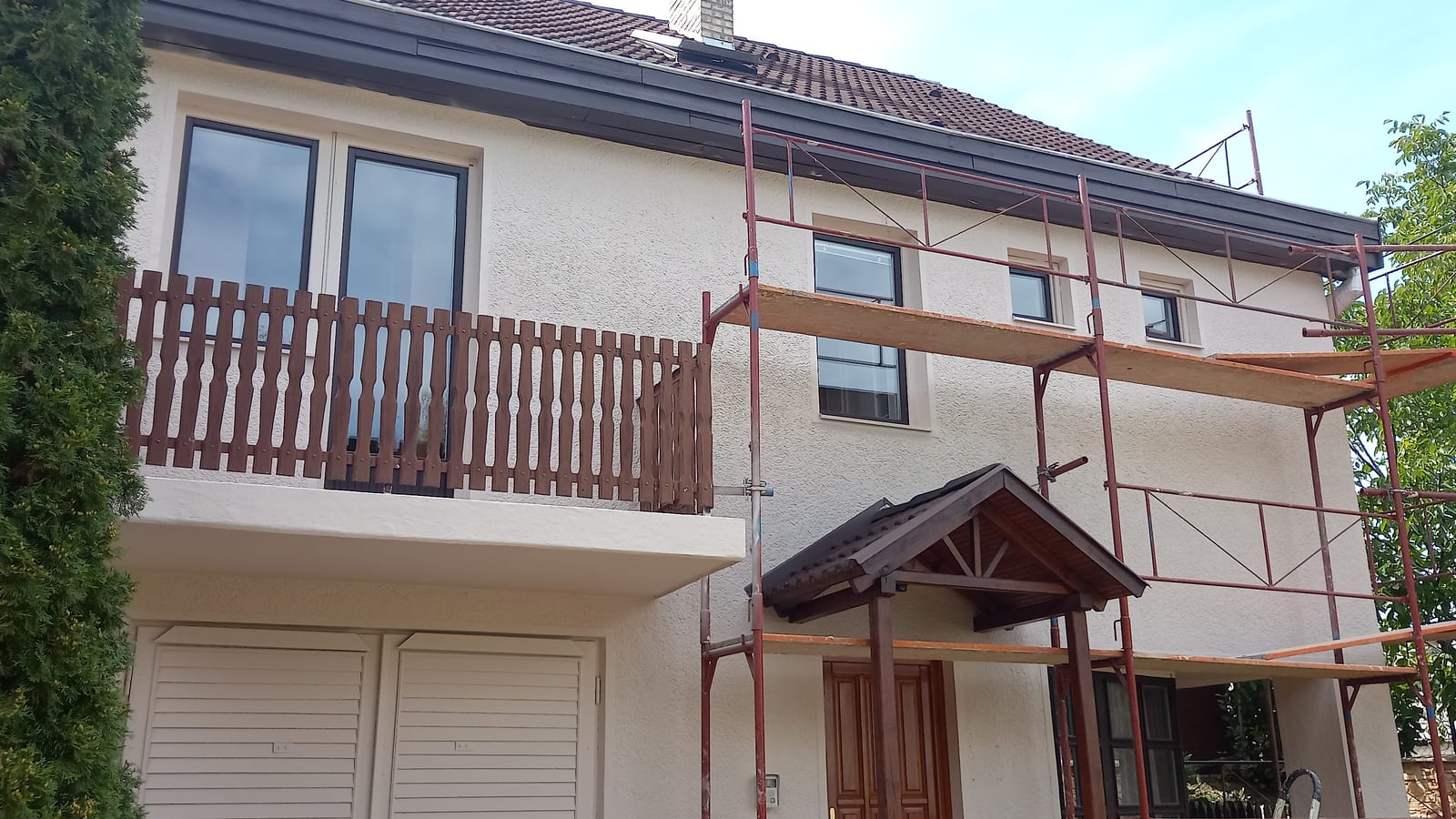 Two-storey family house with a light facade coated with GWR NANO INSULATION®, timber balcony and partial scaffolding, Salgótarján
