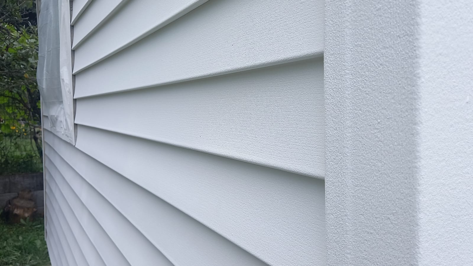 Container house facade with a GWR NANO INSULATION® coating — horizontal board-profile cladding and the adjoining rendered surface in raking light, Pócsmegyer-Surány